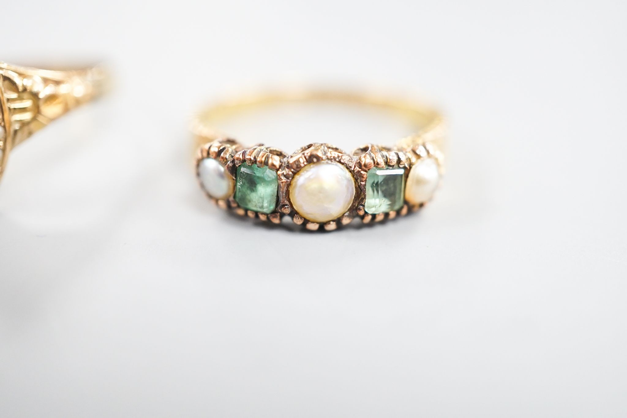 A Victorian 15ct gold, emerald and split pearl set five stone half hoop ring, size M, gross 1.9 grams and an early 20th century yellow metal and seed pearl set dress ring, size O, gross 1.7 grams.